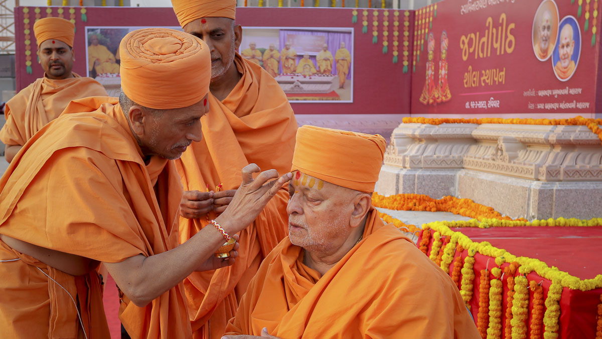 Uttamprakash Swami applies chandan archa to Pujya Ishwarcharan Swami