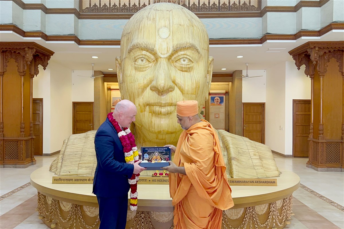 Gnanmuni Swami presents the first print of the Satsang Diksha in Māori, blessed by Mahant Swami Maharaj, to New Zealand Prime Minister Christopher Luxon.