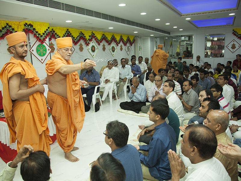 Pujya Ishwarcharan Swami blesses devotees by showering rice grains